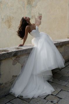 a woman in a white dress leaning against a wall