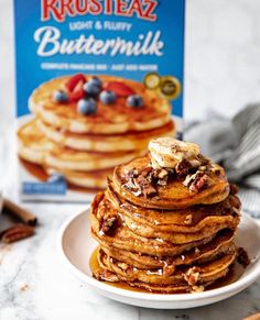 a stack of pancakes on a plate next to a box of buttermilk