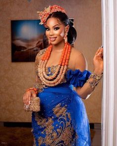 a woman in a blue and gold dress with beads on her head is smiling at the camera