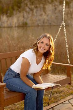 a woman is sitting on a swing reading a book