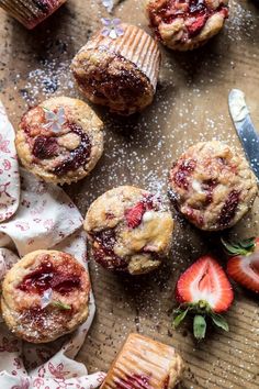 strawberry muffins with powdered sugar and fresh strawberries on the table next to them