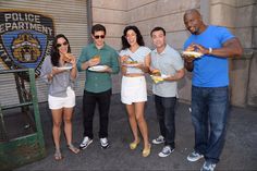 five people standing in front of a police department holding plates of food and posing for the camera