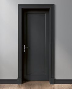 an empty room with a black door and wood flooring on one side, there is a gray wall and wooden floors on the other side