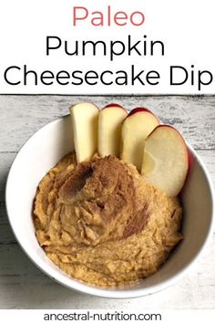 a bowl filled with pumpkin cheesecake dip next to sliced apples and cinnamon on the side