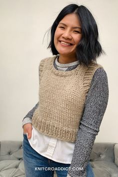 a smiling woman wearing a sweater and jeans