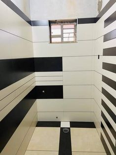 a bathroom with black and white stripes on the walls, toilet paper roll in the middle