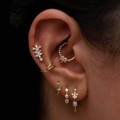 a woman wearing three different ear piercings on her left ear and the other two are gold