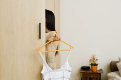 a woman standing in front of a door holding onto a hanger