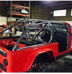 an old red truck is parked in a garage with other vehicles and tools on the shelves