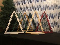 three wooden christmas trees sitting on top of a table next to a wallpapered background