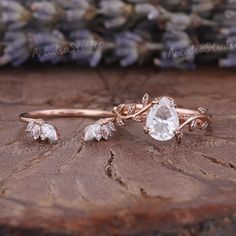 three pieces of jewelry sitting on top of a piece of wood with purple flowers in the background