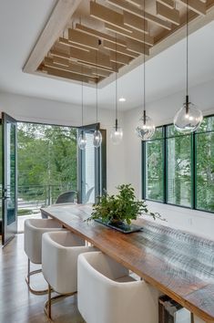 the dining room table is surrounded by white chairs and modern lighting fixtures that hang from the ceiling