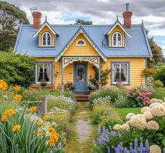 a yellow house with blue roof surrounded by flowers