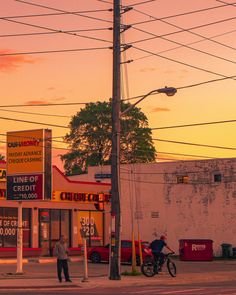 two men are standing on the side of the road in front of some gas pumps