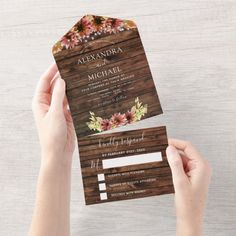 a person holding up a wooden wedding card with flowers on the front and back side