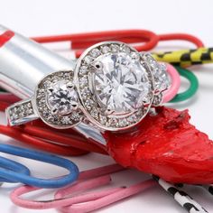 a diamond ring sitting on top of a red object next to some colored crayons