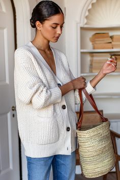 a woman is holding a basket in her hand and looking down at the bag she's holding