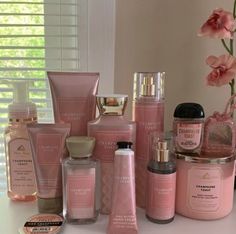 a table topped with lots of different types of skin care products next to a vase filled with flowers