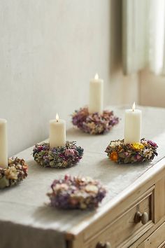 candles are arranged on a table with dried flowers