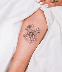 a woman's arm with a bee and flowers tattoo on it