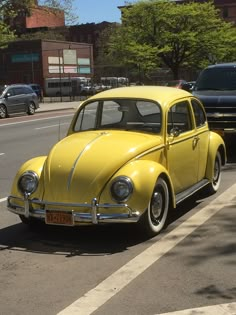 an old yellow car is parked on the side of the road