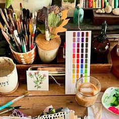 a wooden table topped with lots of art supplies