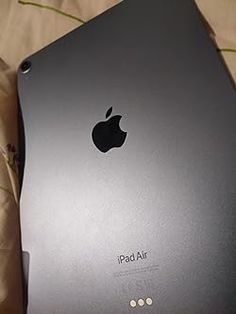 an apple ipad sitting on top of a bed with the cover pulled back to reveal its logo