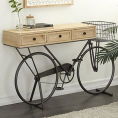 an old fashioned bicycle is sitting on the floor next to a table with two drawers