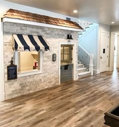 the inside of a house with wood flooring and white brick walls, an awning on the second story