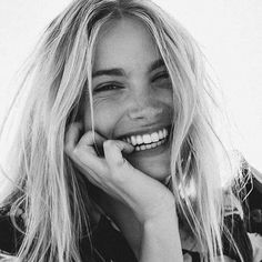 black and white photograph of smiling woman with hand on chin, looking to the side