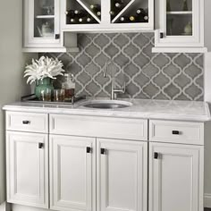 a kitchen with white cabinets and gray tile backsplash, wine rack above the sink