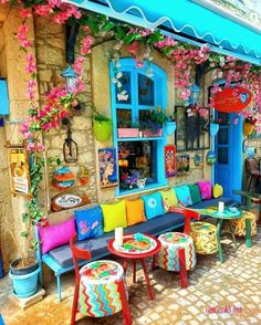 colorful outdoor seating area with flowers on the wall and blue windows in the back ground