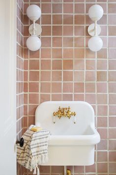 a white sink sitting next to a toilet in a bathroom under two light fixturees