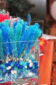 some blue and white candy sticks in a glass vase on a wooden table with other items