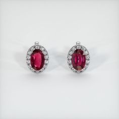 The earrings feature a beautiful, transparent pair of rubies that are 2.92 total carat weight. They are oval shape purplish red rubies, with the dimensions of 8.11 x 5.29 x 4.14 mm and are mixed brilliant cut, have a clarity grade of very slightly included (evaluated at eye level), vivid color saturation, and an excellent polish. #earstuds #earringsstuds #diyearring #earjewelry #earringsjewelry Red Oval Halo Design Earrings, Oval Ruby Earrings With Halo Design, Red Ruby Earrings With Halo Setting, Red Oval Ruby Earrings, Classic Ruby Earrings With Halo Setting, Oval Red Ruby Earrings, Red Ruby Earrings, Cute Ear Piercings, Ruby Earrings