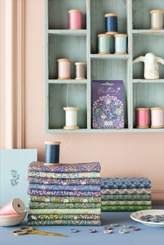 a table topped with lots of different colored spools of thread and sewing supplies