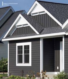 a gray house with white trim and black shingles on the roof, along with two windows