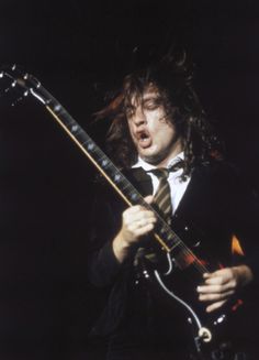 a man with long hair playing an electric guitar