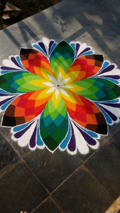 a person standing in front of a colorful flower design on the ground with their feet up