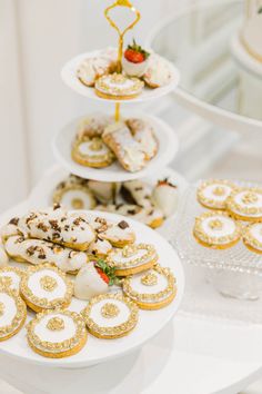 three tiered trays filled with pastries on top of a white tablecloth