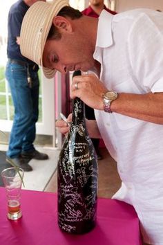 a man is smelling a wine bottle with writing on it