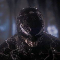 a man in a black suit with his mouth open and an evil looking face on