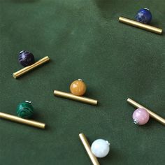 several different colored marbles and gold sticks on a green surface