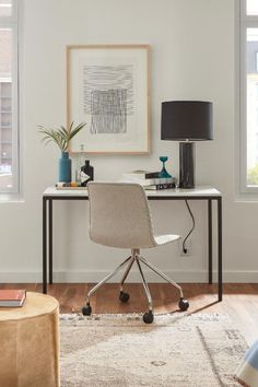 a white desk with a black lamp and some pictures on the wall in front of it