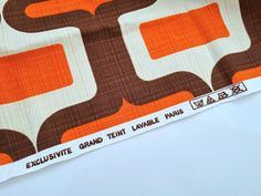 an orange, brown and white fabric with the words executive grand temp table paris on it