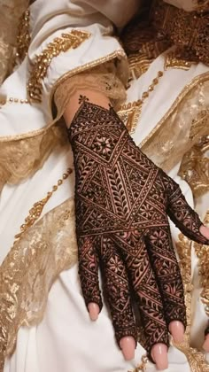 a woman's hand covered in hennap and gold laces on her left arm