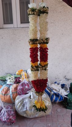 a bunch of flowers that are hanging from a pole in front of some bags on the ground