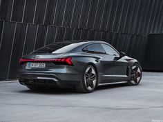 the rear end of an audi car parked in front of a building with black walls