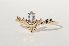 a gold ring with an oval cut diamond and leaves