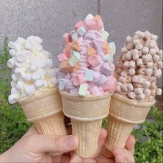 three ice cream cones filled with marshmallows and sprinkles on top